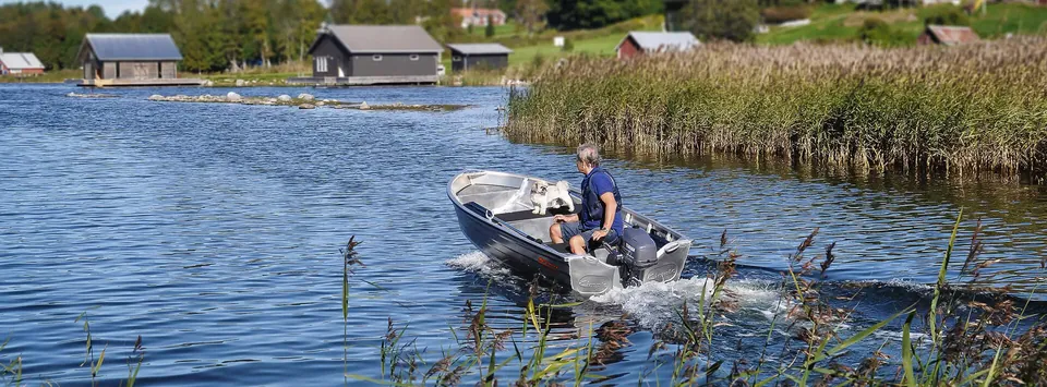 O barcă Kimple din aluminiu navigând pe un lac, aproape de stuf